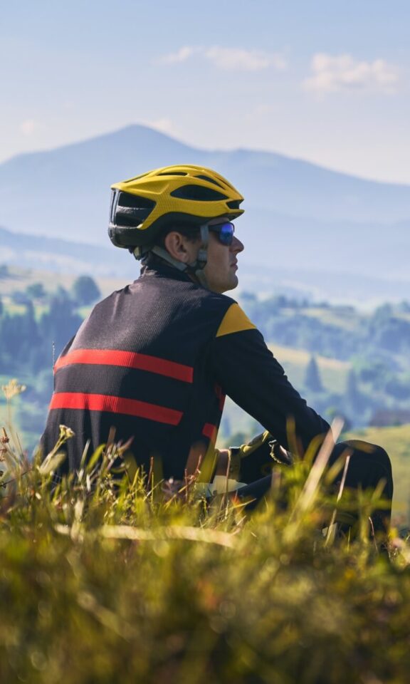 sportgardena-man-cyclist-sitting-grass-looking-mountains-mobile